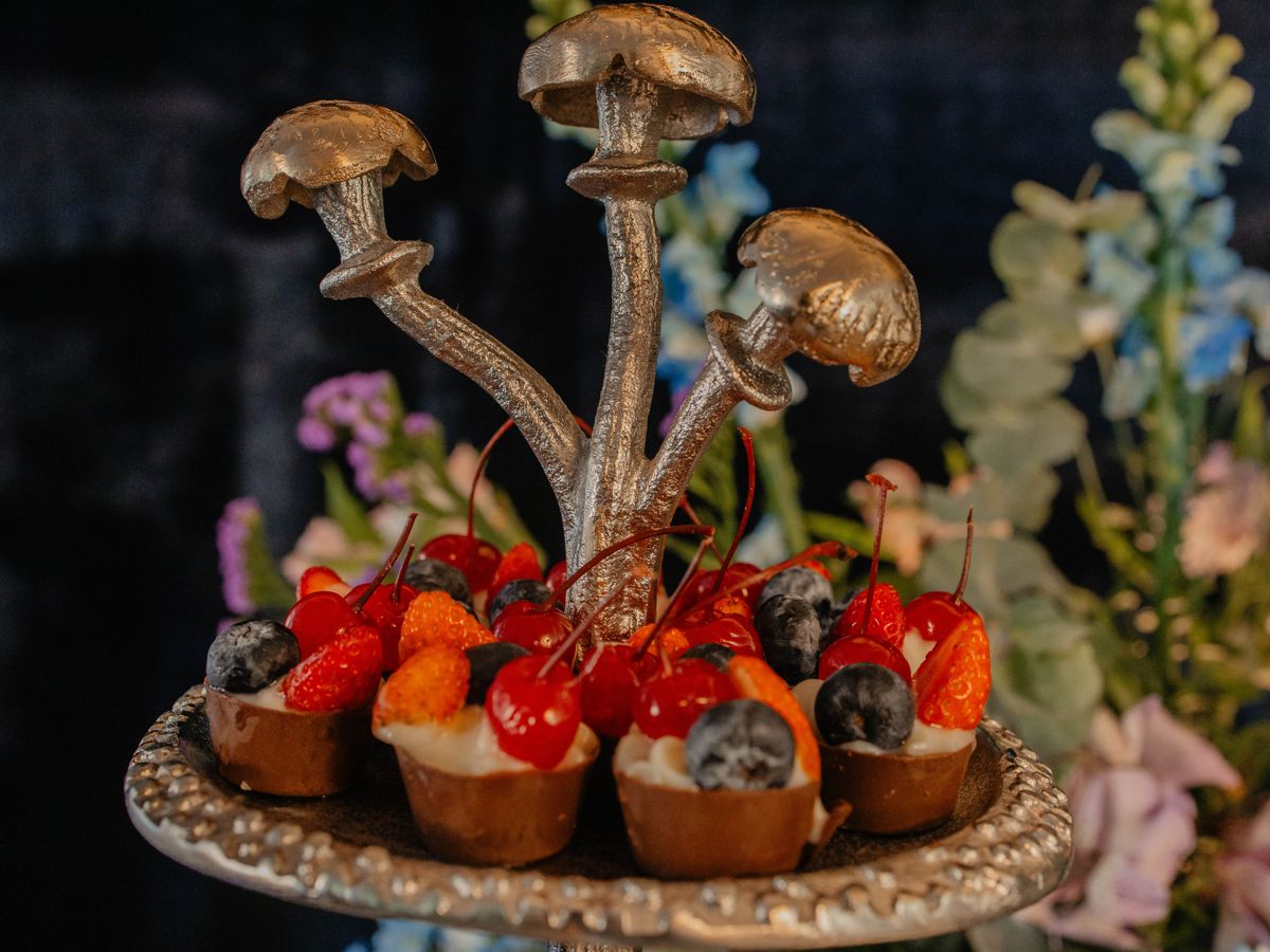 Tortinhas de frutas vermelhas e mirtilo em cestinhas de chocolate, sob um cogumelo prateado