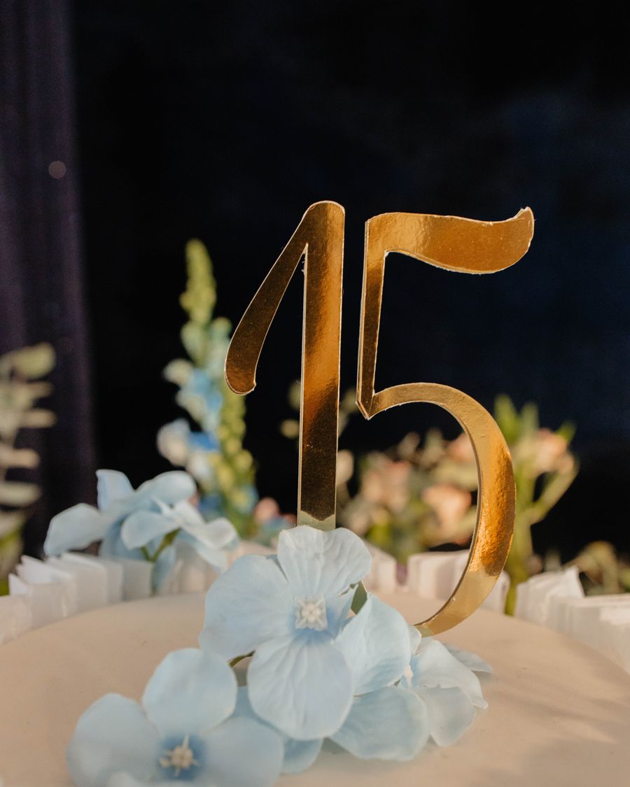O 15 dourado sobre flores azuis.