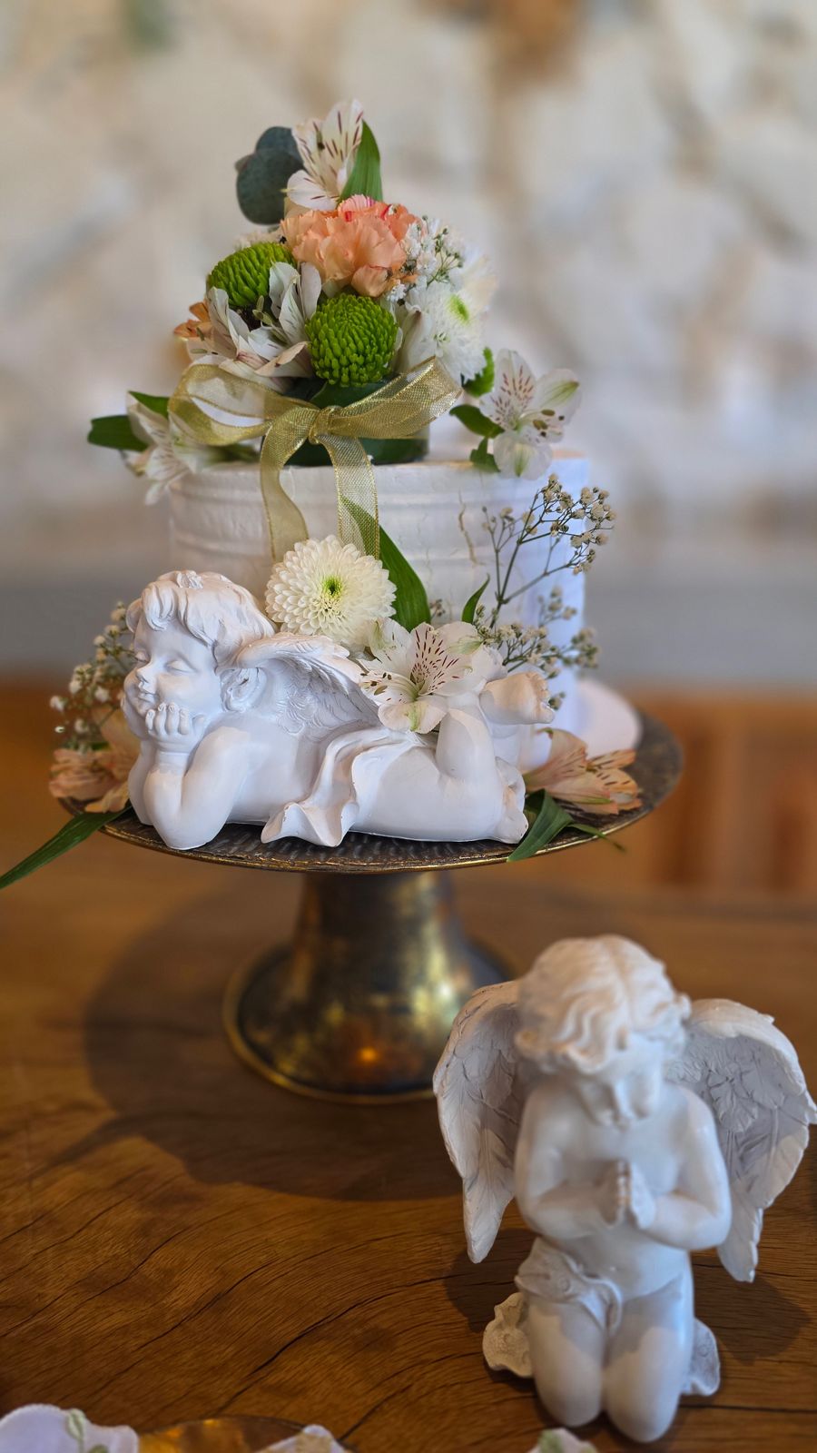 O bolo com anjo e flores, e um anjinho em oração.